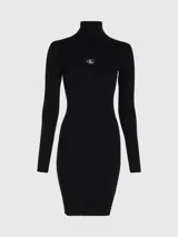 Vestido negro de punto acanalado, corte slim, con cuello tortuga y manga larga. Presenta una pequeña insignia con el monograma de Calvin Klein en el pecho.
