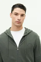 Campera de felpa color verde militar, con cierre frontal, capucha ajustable con cordones y logo estampado en el pecho.