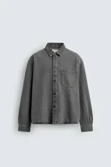 Camisa de denim de algodón, color gris oscuro lavado, de corte holgado (boxy fit). Presenta cuello solapa, manga larga con puño abotonado, bolsillo de plastrón en el pecho y cierre frontal con botones.