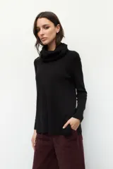 Polera de cuello alto holgado, manga larga y diseño de tejido fino con aberturas laterales en el ruedo.