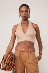 Top halter color beige confeccionado en lino, con escote en V cruzado, tiras medianas y lazada en el frente.