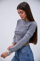 Remera gris de manga larga, con cuello redondo y diseño acanalado.