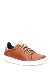 Deportivo de cuero liso color caramelo, con cordones beige y suela blanca. Presenta un detalle metalizado plateado en el talón.