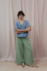 Blusa de lino color fucsia, con escote en V y manga corta amplia. Presenta un detalle de botón decorativo dorado en el centro del escote.