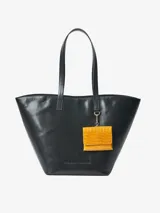 Cartera tipo shopper de cuero vacuno en color negro, con asas largas para hombro y estructura semirrígida. Incluye un pequeño monedero colgante desmontable de cuero texturizado en color mostaza en la parte frontal.
