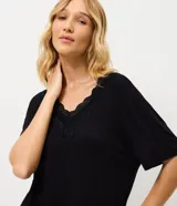 Pijama de dos piezas color negro confeccionado en viscolycra, compuesto por una remera de manga corta con cuello en V y detalles de encaje, y un pantalón capri con cintura elástica.