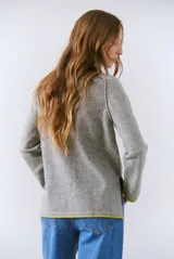 Buzo de tejido de punto color beige, con corte relajado, cuello redondo y mangas largas. Presenta detalles de terminaciones en color azul marino en los puños y en el ruedo inferior.