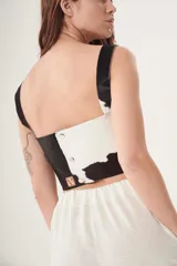 Top corto de cuero ovino con estampado de vaca en blanco y negro, de corte recto y breteles anchos.