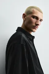 Sobrecamisa de corte relajado confeccionada en tejido de terciopelo elástico, con cuello solapa, manga larga con puños abotonados y cierre frontal de botones.
