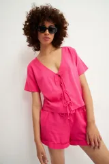 Camisa fucsia de manga corta con escote en V y cierre frontal mediante múltiples lazos anudados.