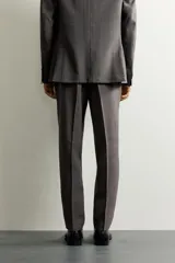 Pantalón de vestir regular fit color gris con sutil patrón a cuadros, confeccionado con mezcla de lana. Cuenta con bolsillos frontales, bolsillos traseros de doble vivo con botón, trabillas para cinturón y raya marcada en las piernas.
