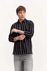 Camisa de manga larga con tejido texturado y diseño a rayas verticales, cuello camisero clásico y cierre frontal con botones.