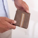 Billetera color beige de símil cuero lisa con galón elastizado marrón con línea blanca. Interior con doble repartición para billetes, visor y tarjeteros.