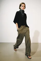 Jeans cargo de tiro medio y corte barrel leg, color verde militar. Presenta bolsillos laterales con solapa en las piernas, bajo ajustable con trabilla y botón, y cierre frontal con cremallera y botón.