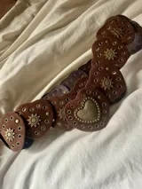 Cinturón tipo faja de cuero sintético color marrón, con apliques de corazones y detalles dorados.