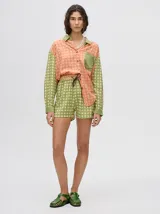 Short de corte boxy confeccionado en viscosa con estampado geométrico de estrellas en tonos rosados. Presenta una pretina elástica en color naranja y cordón de ajuste en color marrón.