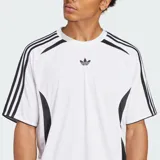 Camiseta deportiva Adidas de manga corta, color blanco, con corte holgado. Presenta el logo del Trifolio en el pecho y las tres rayas negras en los hombros y mangas. Incorpora paneles laterales en malla negra con diseño curvo.
