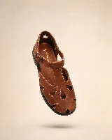 Sandalias de cuero marrón, tipo romanas, con calados orgánicos en la capellada, puntera semi cerrada, tira en T y pulsera regulable con hebilla metálica. Poseen taco bajo y costuras pespunteadas a contratono.