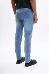 Pantalón de jean celeste de corte slim, con efecto lavado, bolsillos clásicos y cierre frontal de botón y cremallera.