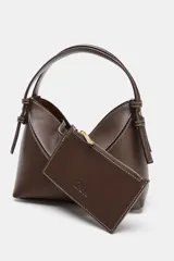 Bolso mini shopper de diseño trenzado en color beige, con asas de mano y correa bandolera extraíble en tono marrón. Presenta detalle de pespuntes en contraste y cierre interior con cremallera.