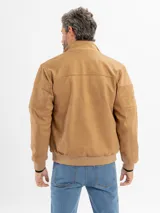 Campera de estilo casual confeccionada en tejido suave con textura tipo gamuza. Presenta cuello alto, cierre frontal, bolsillos laterales y bolsillos frontales con solapa. Incluye detalles de costuras en las mangas y terminaciones elastizadas en puños y cintura.