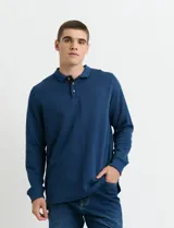 Remera de punto canalé con cuello polo, manga larga y cierre frontal con botones de madera. Presenta un diseño con cartera a contratono y medialuna interior.
