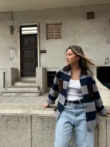 Camisa gris con rayas horizontales azul marino, cuello y bolsillos de cuero marrón, y cierre frontal con botones.