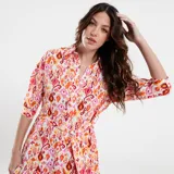 Vestido corto con cuello mao, mangas 3/4 y falda con volados. Estampado con motivos geométricos en tonos naranja, rosa y blanco. Incluye cinturón fino del mismo tejido.