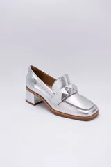 Mocasines plateados de cuero con aplique geométrico al tono y taco cuadrado.