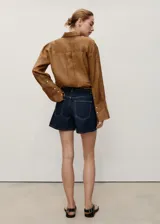 Short de denim azul oscuro, de tiro alto y corte recto, con cinco bolsillos, trabillas y cierre frontal con cremallera y botón.