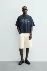 Camiseta de manga corta, cuello redondo y calce relajado, confeccionada en tejido con estructura waffle de color azul marino. Presenta estampados y bordados combinados a contraste en el delantero con texto en blanco.