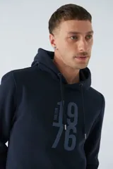 Buzo canguro azul marino con capucha ajustable, bolsillo canguro, fit regular, arte estampado en relieve, logo en goma y composición de 80% algodón y 20% poliéster.