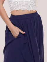 Falda larga de color blanco con pretina elastizada y fruncidos en la cintura, con caída holgada y ligera.