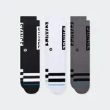 Pack de tres pares de medias deportivas Stance, caña media, con diseño de rayas gruesas en el tobillo y logo vertical en la caña. Incluye un par negro, uno blanco y uno gris.