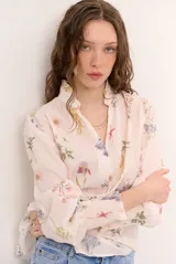 Camisa de manga larga color arena con delicado estampado floreado, cuello mao con volados, escote en V con botones frontales y puños fruncidos elastizados.