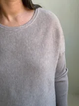 Sweater de punto en color visón, con cuello redondo, manga larga y diseño holgado con aberturas laterales en el ruedo.
