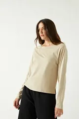 Remera manga larga color beige, con cuello bote y corte recto a la altura de la cadera.