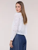 Chaqueta corta de calce recto en tejido broderie blanco, con diseño calado de perforaciones geométricas y florales, escote redondo, frente abierto y mangas largas.