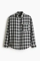 Camisa de corte relajado, confeccionada en mezcla de algodón suave con diseño a cuadros difuminados en tonos negro y blanco. Cuenta con cuello inglés, cierre frontal de botones, bolsillo en el pecho y mangas largas con puños abotonados.
