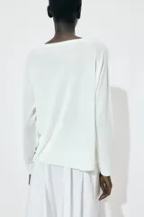 Jersey de punto liso, color azul brillante, con cuello redondo y manga larga. Presenta acabados en rib en puños, cuello y bajo, con aberturas laterales en el ruedo.