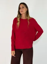 Sweater de punto color rojo con detalle de pequeñas lentejuelas brillantes dispersas, de cuello redondo, manga larga y corte holgado con ruedo asimétrico.
