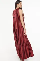 Vestido largo de viscosa color bordó, con cuello halter alto, corte holgado y volante fruncido en el bajo.