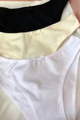 Kit de tres bombachas clásicas de algodón elastizado, tiro medio y detalle de moño en el centro. Incluye una bombacha negra, una color crema y una blanca.