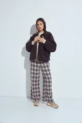 Campera de corderito color marrón oscuro, con cuello camisero y cartera frontal en tela lisa a tono. Presenta cierre mediante botones a presión y mangas largas con puños elásticos.