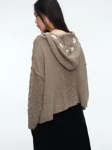 Buzo de tejido de punto con diseño de ochos, capucha integrada con cordones ajustables en contraste, manga larga y corte holgado.