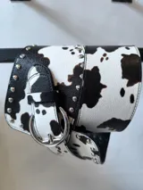 Faja ancha con estampado de vaca, con hebilla metálica y tachas decorativas.
