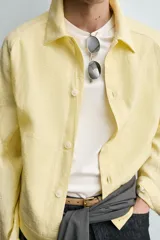 Sobrecamisa relaxed fit de color amarillo claro, confeccionada en tejido con mezcla de lyocell. Presenta cuello solapa, mangas largas raglán con puños abotonados, bolsillos de vivo en la cadera y cierre frontal con botonadura.