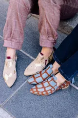 Botín artesanal de piel de potro con estampado animal print tipo jirafa en tonos marrón y azul. Presenta diseño de dos piezas con bordes troquelados, aberturas laterales y detalle de borlón trasero en ante azul. Incluye cuña interna y suela de cuero.