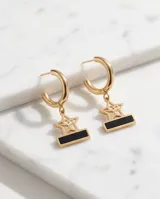Aros tipo argolla de acero dorado con dije colgante en forma de estrella calada y barrita horizontal con detalle en esmalte negro.