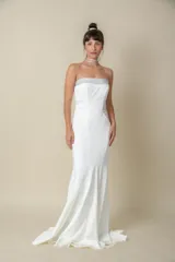 Vestido largo blanco de crepé, corte sirena, palabra de honor con bordado de piedras en el escote y cola pequeña.